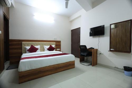 a bedroom with a bed and a desk and a television at Hotel Classic Crown in Jaipur