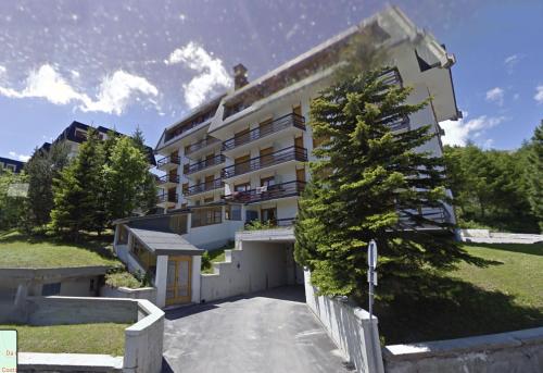 un bâtiment avec un arbre devant lui dans l'établissement Casa Rossa - Italian Style in Sestriere, à Sestrières