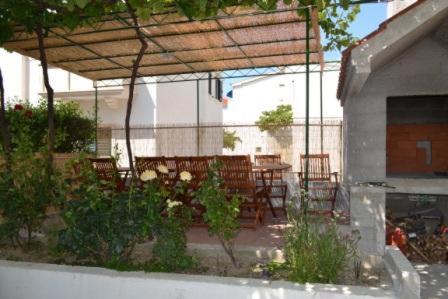 a patio with a table and chairs and a wooden roof at Apartments Karlo in Omiš