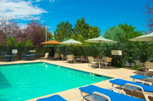 a swimming pool with chairs and tables and umbrellas at SpringHill Suites by Marriott Boise ParkCenter in Boise