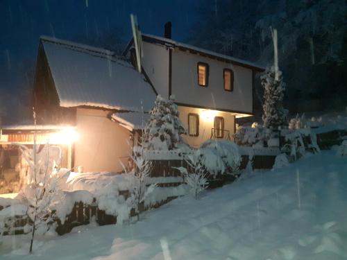 a house covered in snow at night with lights at Restaurant and Apartments - T'ga za Jug Lazaropole in Lazaropole