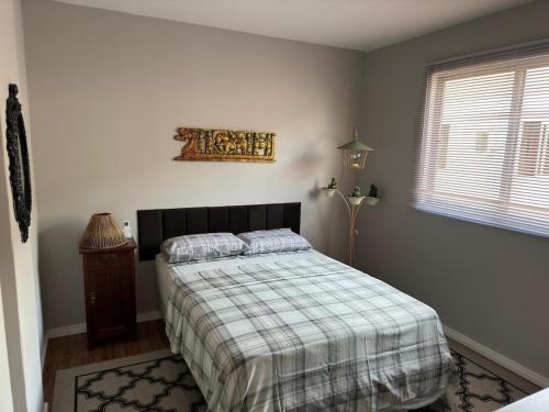 a bedroom with a bed with a plaid blanket and a window at Apartamento 2 quartos com ar-condicionado, sacada com churrasqueira no centro in Balneário Camboriú