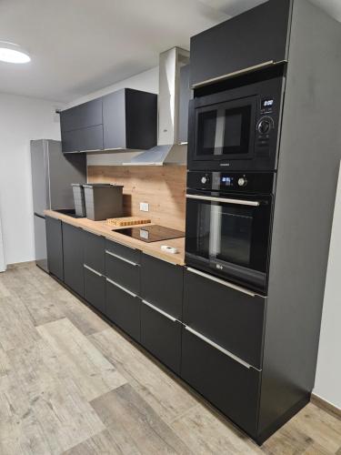 une cuisine avec des armoires noires et un four micro-ondes dans l'établissement la chtite famille, à Le Portel