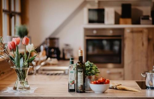 two bottles of wine sitting on a kitchen counter with tomatoes at Luxuriöse Schwarzwald Loft Heustock mit Sauna und Whirlpool am Griesbachhof in Titisee-Neustadt