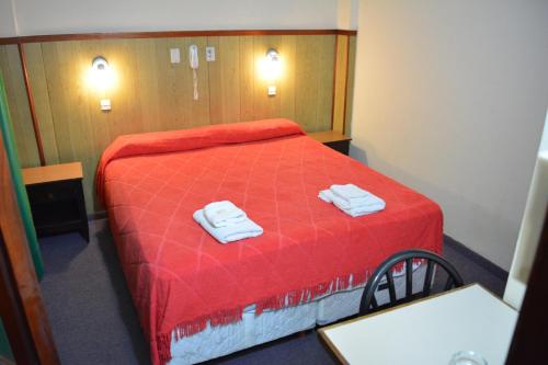 1 dormitorio con 1 cama roja y 2 toallas en Gran Hotel Amelia en Mar del Plata