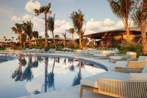 a resort pool with lounge chairs and palm trees at The St. Regis Red Sea Resort in Ḩanak