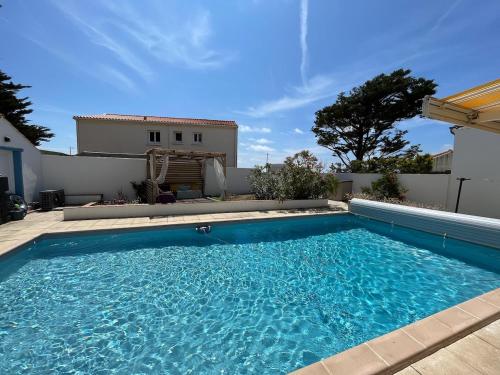 une grande piscine bleue devant une maison dans l'établissement Idéal vacances en famille, à Bretignolles-sur-Mer