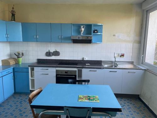 kuchnia z niebieskimi szafkami i niebieskim stołem z krzesłami w obiekcie Location maison à Chadron : Haute Loire w mieście Chadron
