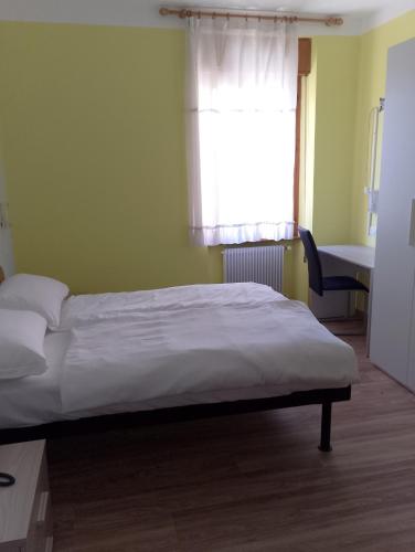 a bedroom with a bed with a window and a desk at Hotel Garden in Levico Terme