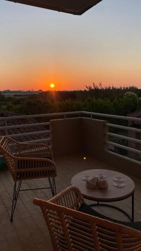 a patio with a table and chairs and a sunset at Lali's Country House in Amaliás
