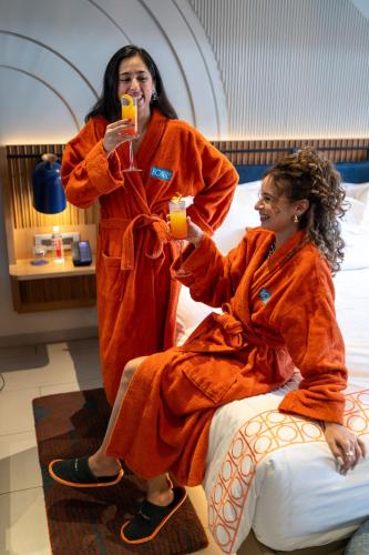 two women dressed in orange robes drinking orange juice at Hyatt Ronil Goa - a JdV by Hyatt Hotel in Calangute