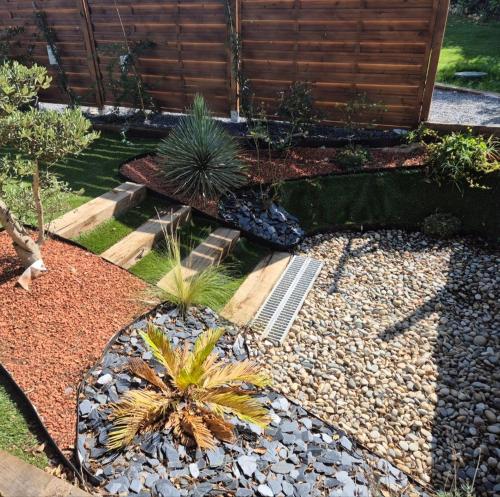a garden with palm trees and rocks and a fence at Maison mitoyenne et independante in Aubais