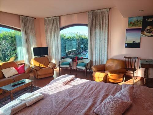 a bedroom with a bed and chairs and a living room at Alloggio nella Villa dell'Edera in Acqui Terme