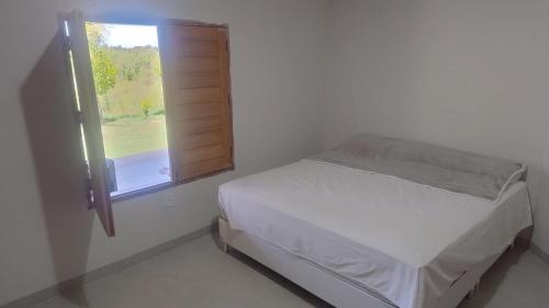 a white bedroom with a bed and a window at Sítio Recanto dos pássaros in Porto Seguro