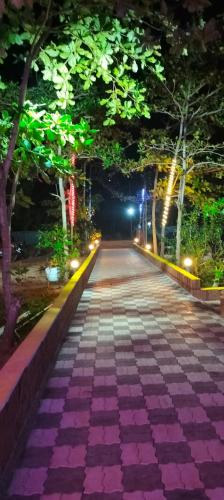 an empty street at night with trees and lights at White Sand beach Stay Resort in Kumta