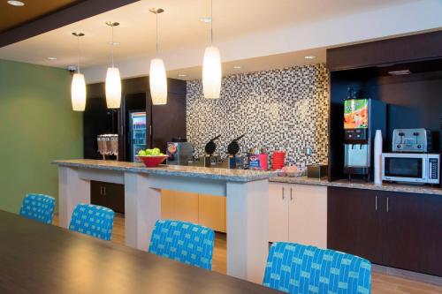 a kitchen with a bar with blue chairs and a table at TownePlace Suites by Marriott Lexington South/Hamburg Place in Lexington