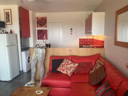 un salon avec un canapé rouge et une cuisine dans l'établissement CapNat - Village Naturiste - Port Nature - Appartement 2 pieces - Le Bowie, au Cap d'Agde