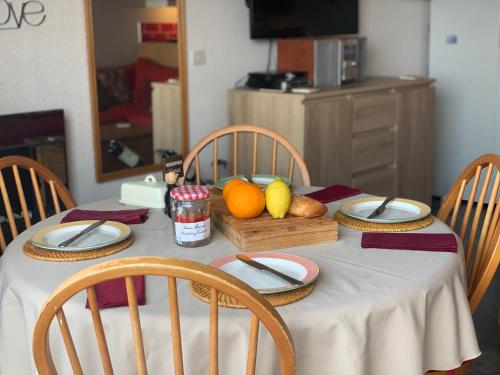 une table avec un chiffon de table blanc et des fruits dessus dans l'établissement CapNat - Village Naturiste - Port Nature - Appartement 2 pieces - Le Bowie, au Cap d'Agde