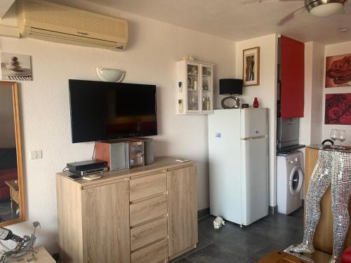 - un salon avec une télévision et un réfrigérateur dans l'établissement CapNat - Village Naturiste - Port Nature - Appartement 2 pieces - Le Bowie, au Cap d'Agde