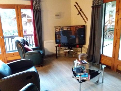 - un petit enfant assis dans un salon avec une table en verre dans l'établissement Joli chalet dans la forêt, à Formiguères