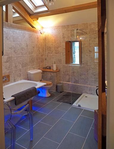 a bathroom with a tub and a toilet and a sink at The Cow House in Shap