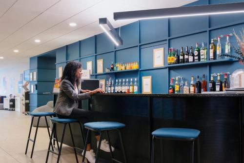 a woman sitting at a bar in a liquor store at ibis Styles Nancy Centre Gare in Nancy