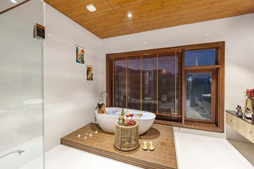 a bathroom with a tub and a glass shower at ELIVAAS Prive 5 BHK Kvanya Mansion with Pvt Pool & Home Theater in Debāri
