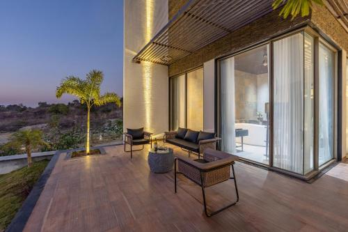 a patio with a couch and chairs and a tree at ELIVAAS Prive 5 BHK Kvanya Mansion with Pvt Pool & Home Theater in Debāri