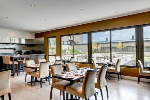 un ristorante con tavoli, sedie e finestre di Auberge Du Vin, a Tribute Portfolio Hotel a Tupungato