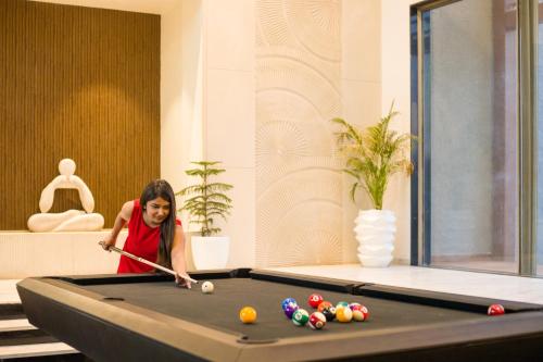a woman playing pool on a pool table at ELIVAAS Prive 5 BHK Kvanya Mansion with Pvt Pool & Home Theater in Debāri