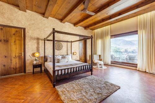 a bedroom with a canopy bed and a large window at ELIVAAS Prive 5 BHK Kvanya Mansion with Pvt Pool & Home Theater in Debāri