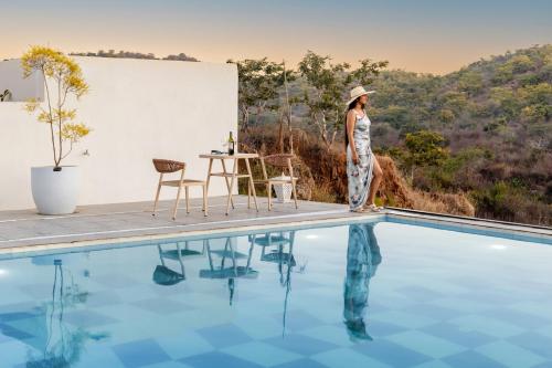 a woman standing next to a swimming pool at ELIVAAS Prive 5 BHK Kvanya Mansion with Pvt Pool & Home Theater in Debāri