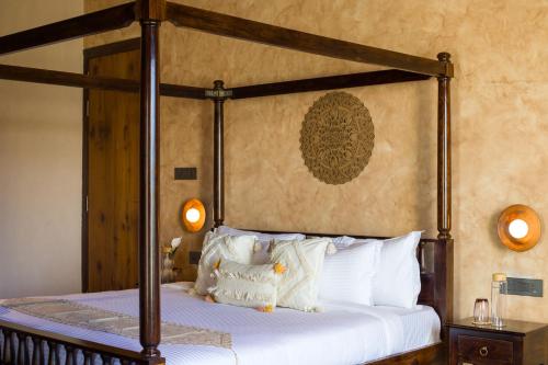 a bedroom with a canopy bed with white pillows at ELIVAAS Prive 5 BHK Kvanya Mansion with Pvt Pool & Home Theater in Debāri