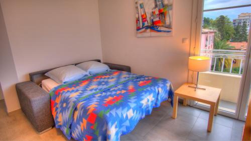 une chambre avec un lit avec une couette colorée et une fenêtre dans l'établissement Beau 2 pièces 3 étoiles Vue Mer Garage Privé 150m plages wifi, à Cannes