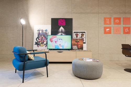 a living room with a tv and a blue chair at ibis Styles Nancy Centre Gare in Nancy
