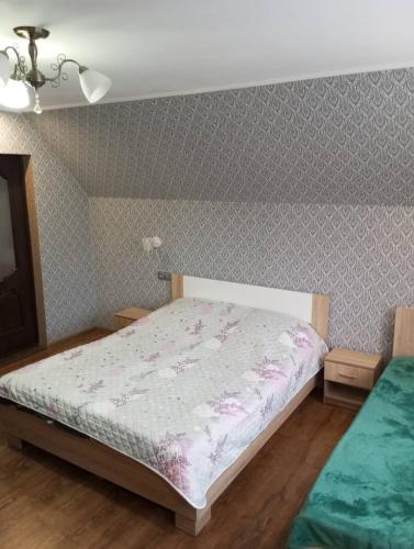 a bedroom with a bed with a floral bedspread at Біля Річки in Kvasy