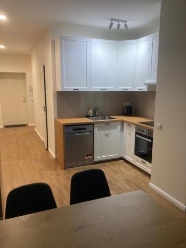 a kitchen with white cabinets and a table and chairs at Maleva Stay at - two room apartment in Tallinn