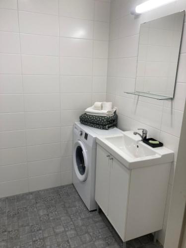 a white bathroom with a washing machine and a sink at Maleva Stay at - two room apartment in Tallinn