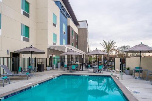 a pool at a hotel with chairs and tables and umbrellas at TownePlace Suites by Marriott Merced in Merced