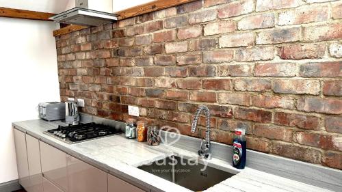 a brick wall behind a kitchen counter with a sink at Old Boathouse 3 Bed 2 Bath Nr Beach Inc Parking in Broadstairs
