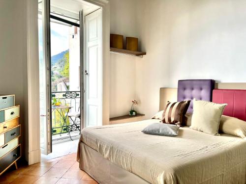 Schlafzimmer mit einem Bett mit einem lila Kopfteil und einem Balkon in der Unterkunft iMinerva Garden Panoramic Suite in Salerno