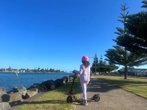 a woman standing next to a scooter next to the water at Devonport Breeze Escape in Devonport