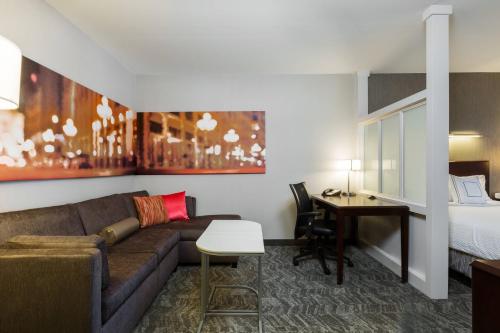 a living room with a couch and a desk and a bed at SpringHill Suites Indianapolis Fishers in Indianapolis