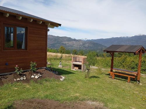 a log cabin with a bench and a grill at Cabaña Los Chochos in Lago Puelo