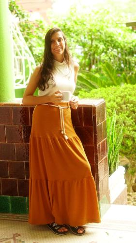 a woman in an orange skirt sitting on a brick wall at POA Eco Hostel in Porto Alegre