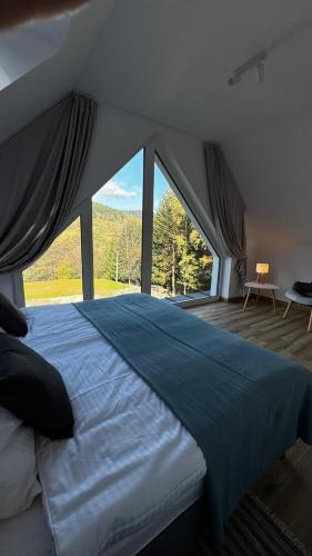 a bedroom with a large bed with a large window at Domki na Stronie C in Stronie Śląskie