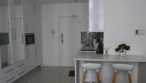 a kitchen with white cabinets and a counter with stools at ITowers Luxury Apartment 1 in Gaborone