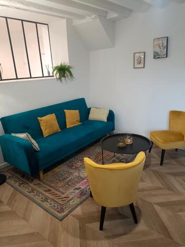 un salon avec un canapé bleu et un fauteuil jaune dans l'établissement La Maison de Juliette maison entière avec garage et terrain, à Condé-sur-Sarthe