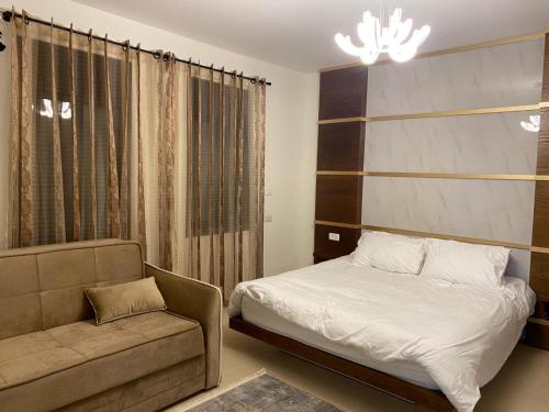 a bedroom with a bed and a couch and a chandelier at The Queen Guest House in Majdal Shams