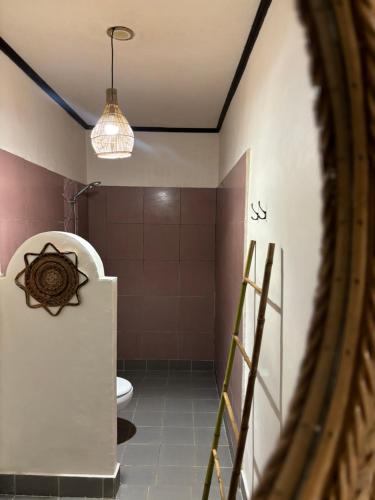 a bathroom with a toilet and a pendant light at Little Pearl in Gili Trawangan